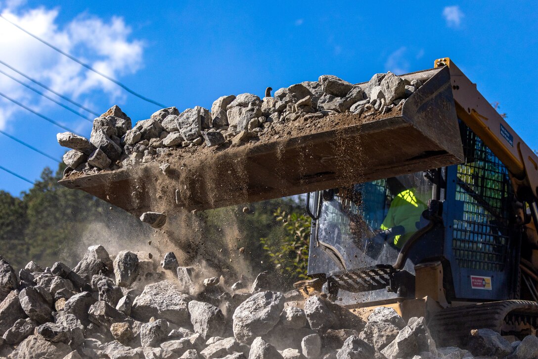 In a flood protection-project channel, a construction worker uses a bulldozer to move riprap.
