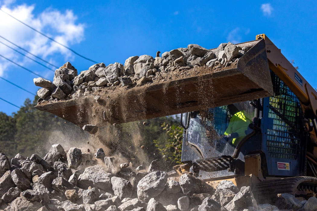 In a flood protection-project channel, a construction worker uses a bulldozer to move riprap.
