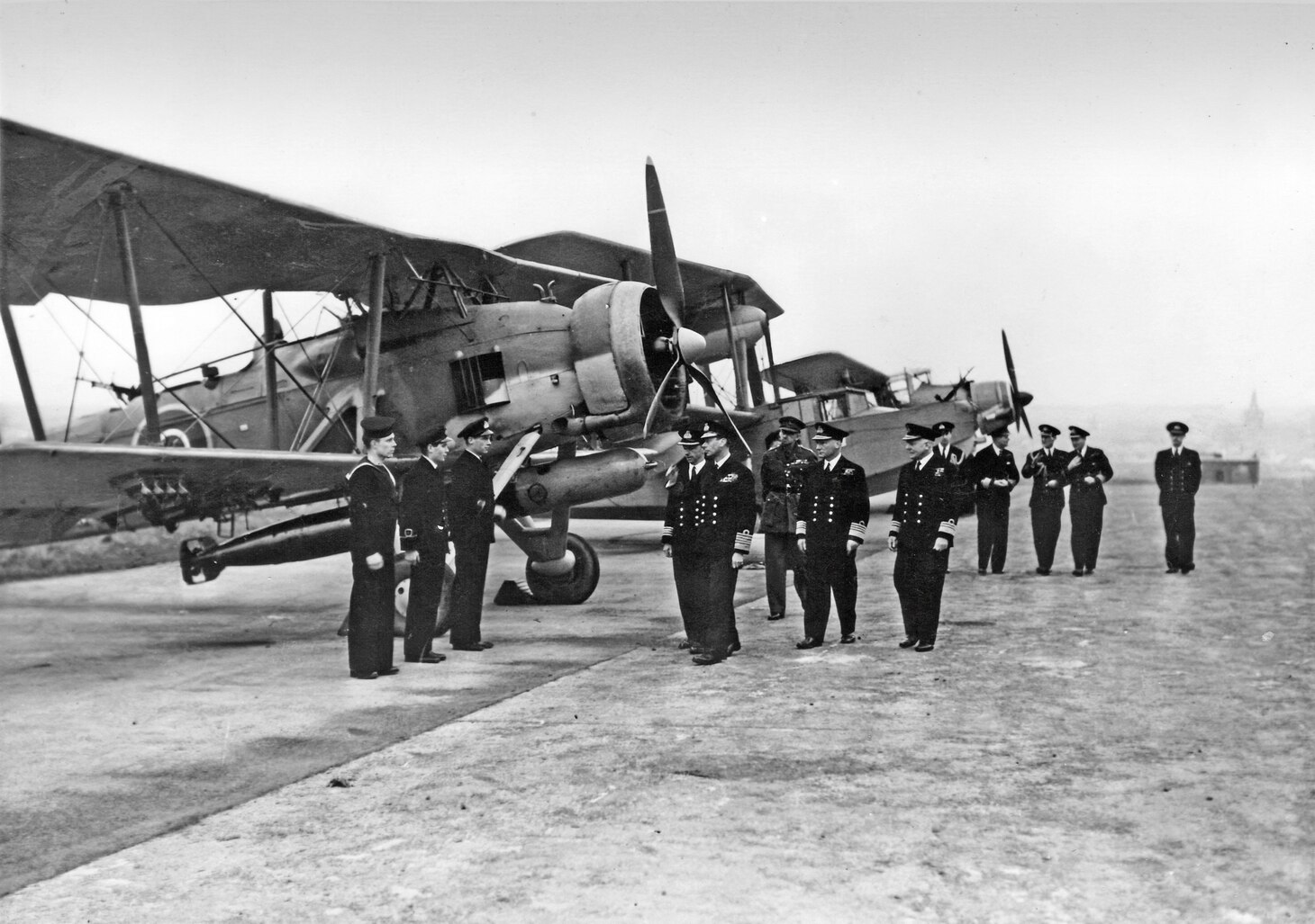 England’s King George VI (fifth from the left) inspects a lineup of aircraft, including a Swordfish (on the left), a Walrus and an Albacore.