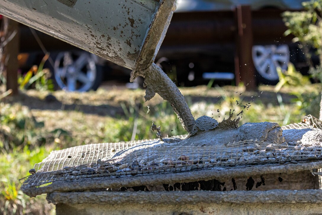 In a flood protection-project channel, a construction worker pours concrete.