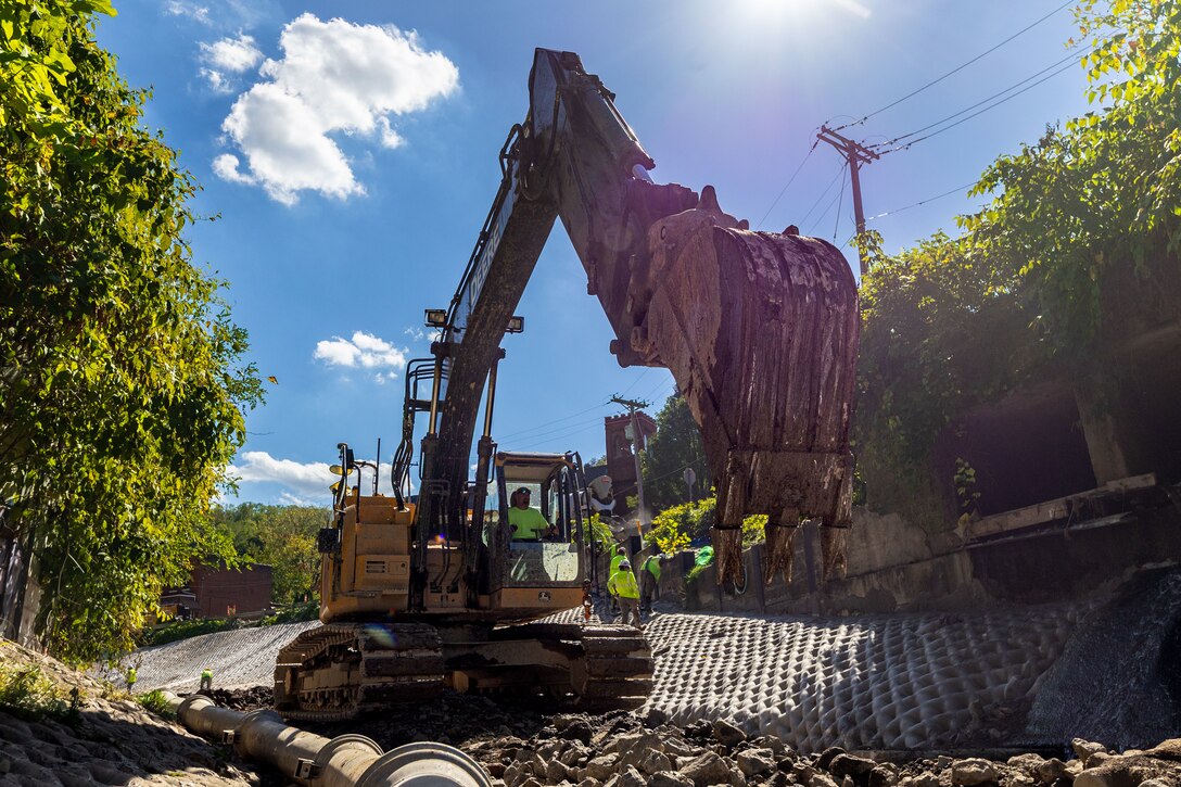 In a flood protection-project channel, a construction worker operates an excavator.