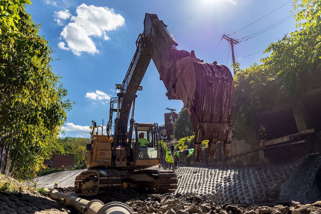 In a flood protection-project channel, a construction worker operates an excavator.