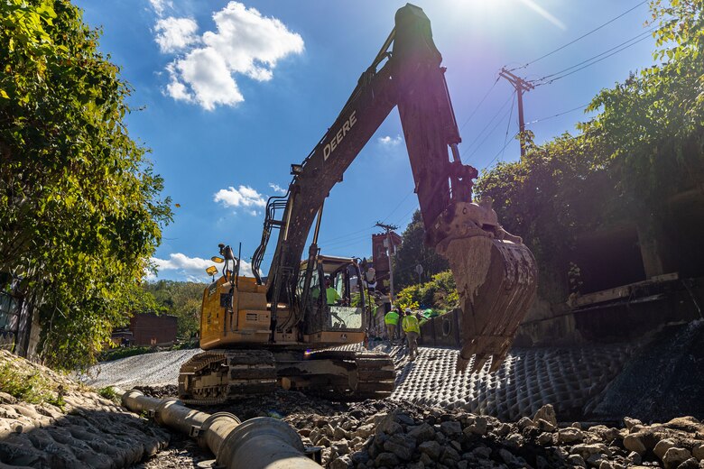 In a flood protection-project channel, a construction worker operates an excavator.