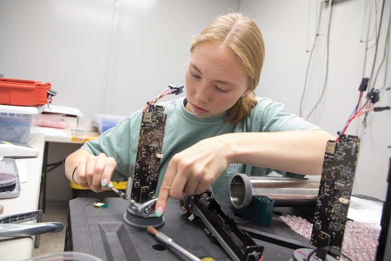 A student researcher prepares sensors for mounting.