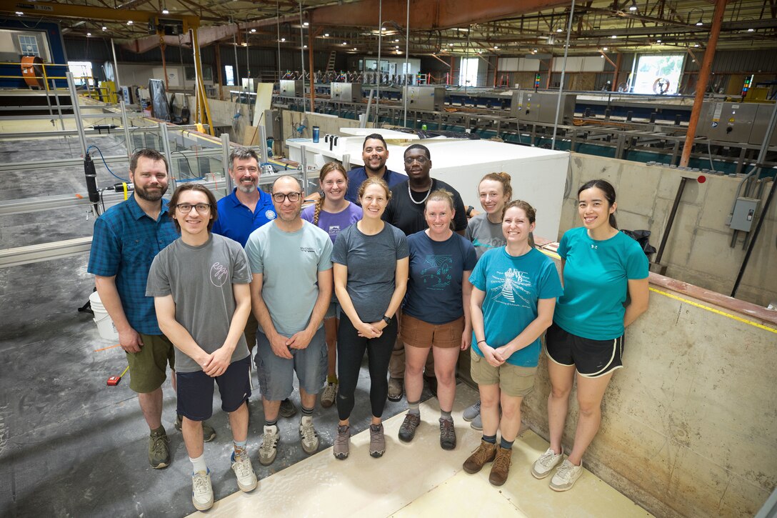 A group of research students and advisors pose in a flume during the U.S. Coastal Research Program’s Sediment Transport Collaborative Laboratory Experiment