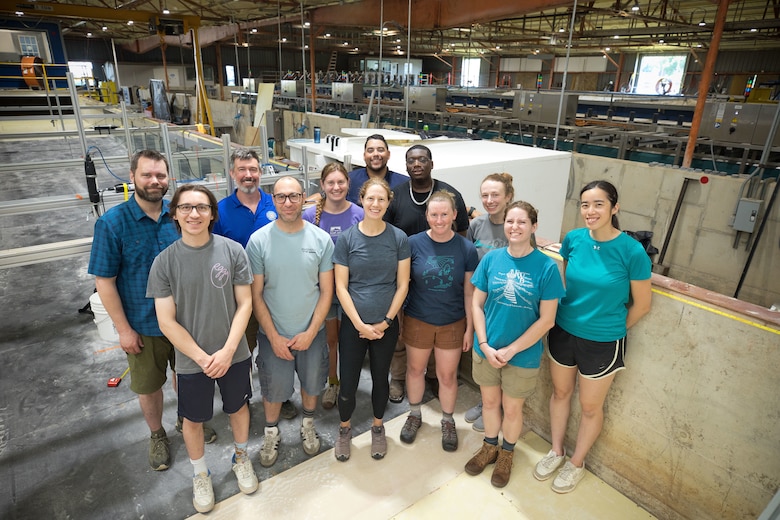 A group of research students and advisors pose in a flume during the U.S. Coastal Research Program’s Sediment Transport Collaborative Laboratory Experiment