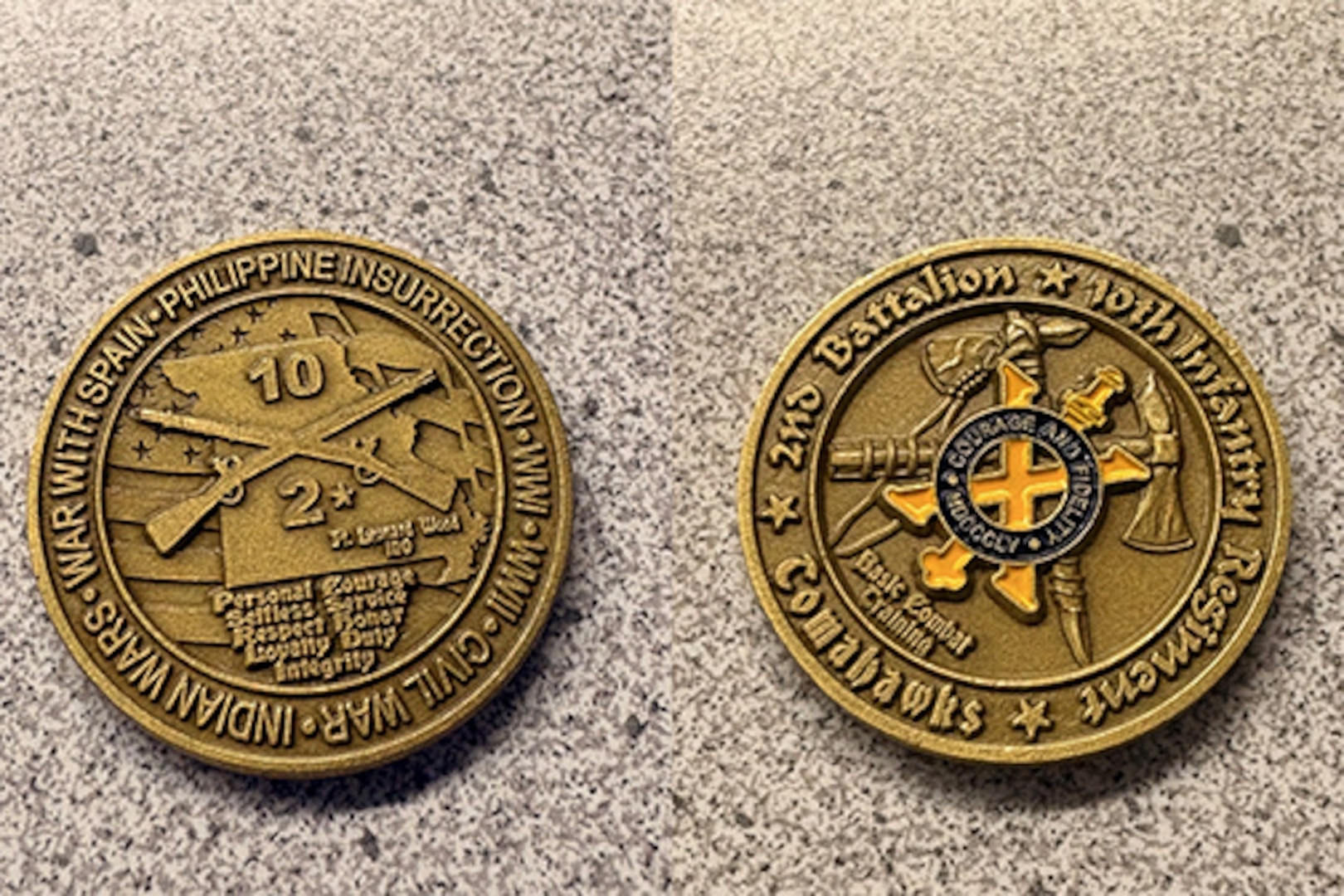 Two sides of a coin, one side has crossed muskets and the out like of the state of Missouri the other side has a yellow X and crossed tomahawks.