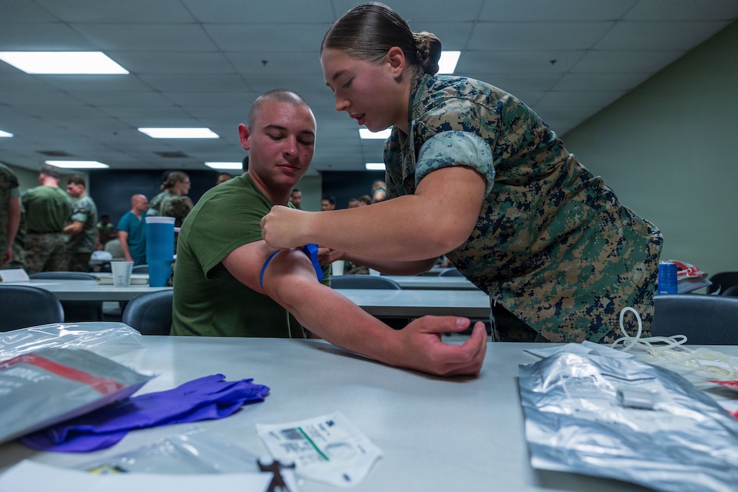 U.S. Navy Hospitalman Samantha Robinson with Weapons Company, Battalion Landing Team 3/5, 11th Marine Expeditionary Unit, demonstrates how to draw a patient’s blood during a transfusion demonstration as part of combat medical training on Marine Corps Base Camp Pendleton, California, Oct. 8, 2025. This training enhances battlefield medical care skills and patient stabilization techniques. (U.S. Marine Corps photo by Lance Cpl. Nicole Stuart)
