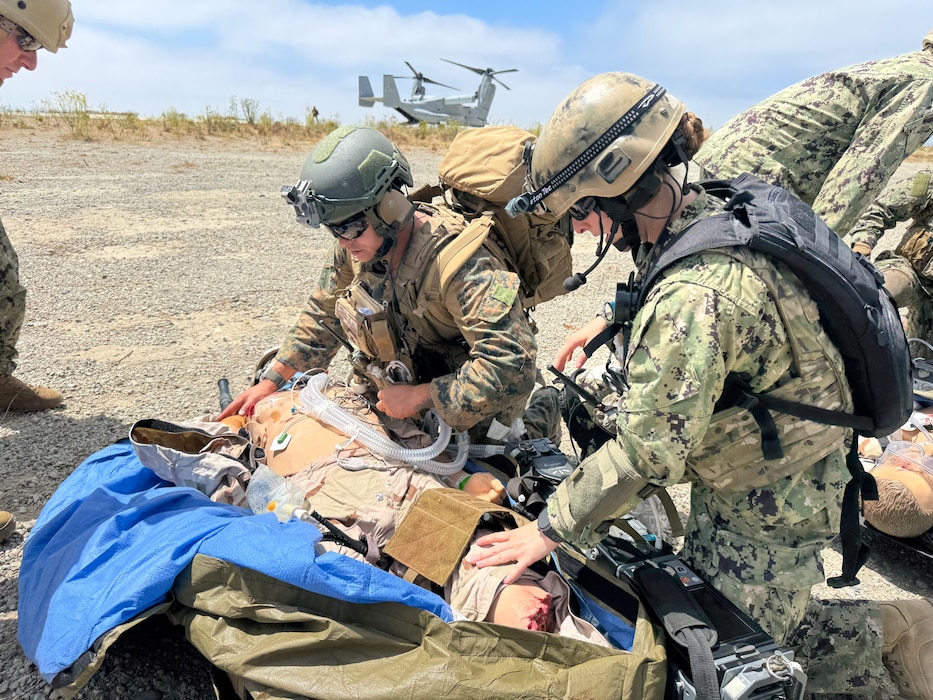 Lt. Hannah Cunningham (right), Joint En-Route Care Course (JECC) critical care nurse, and Hospital Corpsman 1st Class Paramedic Daniel Rodriguez (left) from ERCS 52,  assess a simulated casualty during an En-Route Care System (ERCS) training scenario conducted by Naval Expeditionary Medicine Warfighter Development Center (NEMWDC), Aug. 12-19, 2025. The team collaborated with the 15th Marine Expeditionary Unit (15th MEU) to integrate an MV-22 Osprey into the exercise, creating a highly realistic training environment that allowed the team to practice patient loading procedures, coordinate with aircrew, and engage in expeditionary medical evacuation operations. (U.S. Navy photo by Petty Officer 2nd Class Taylor Plantikow)