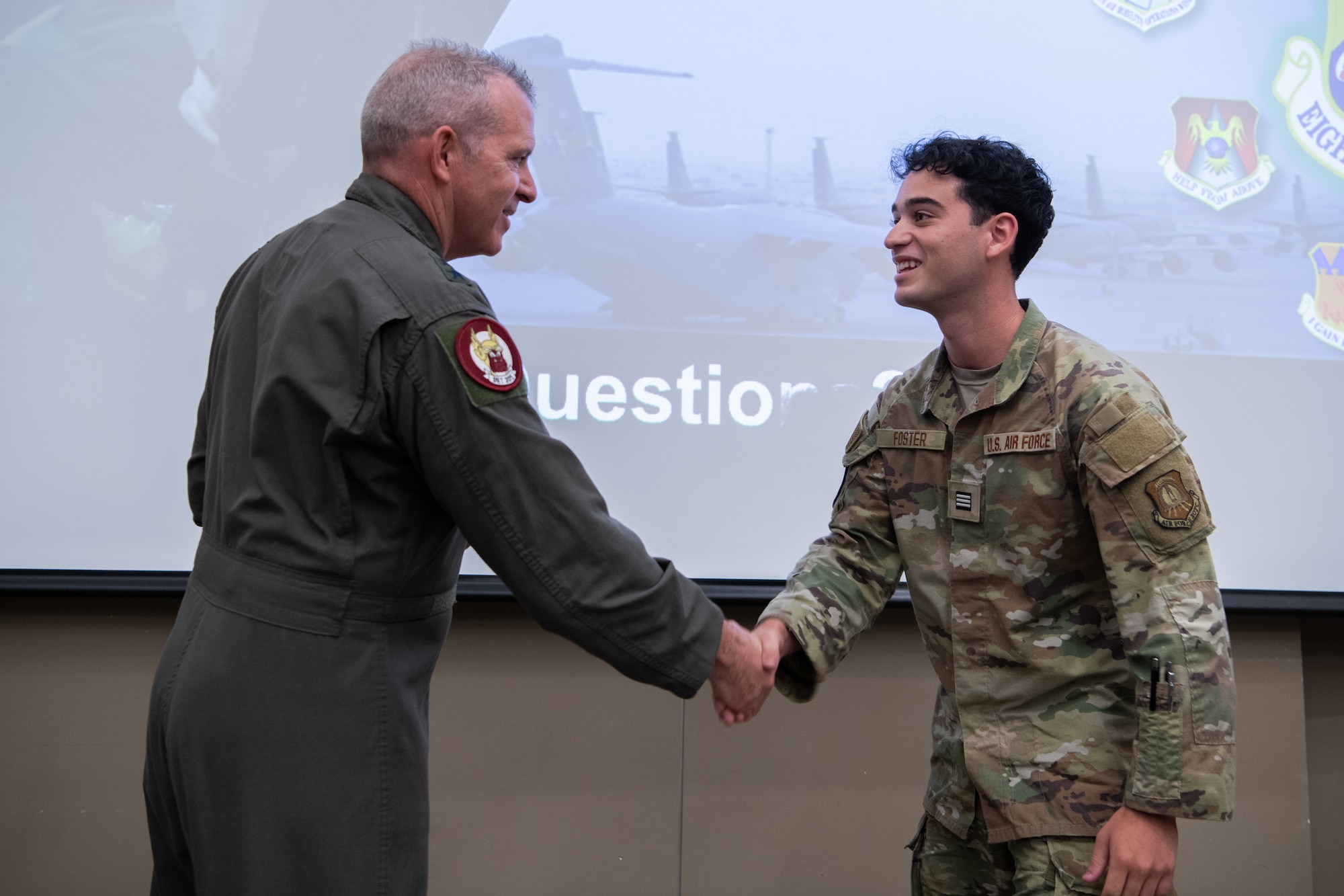 two people standing in front of screen shaking hands