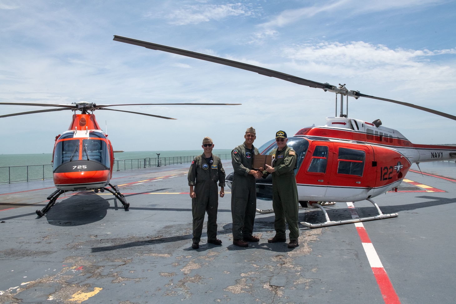 Capt. Travis Suggs, operations officer of Chief of Naval Air Training, left, and Cmdr. James Gelsinon, commanding officer of Helicopter Training Squadron (HT) 28, center, present a TH-57C Sea Ranger aviation log book to retired Capt. Steve Banta, executive director of the USS Lexington Museum on the Bay, as part of a ceremonial turnover after landing the aircraft on decommissioned aircraft carrier USS Lexington (CV 16) Museum on the Bay. This landing commemorates the legacy of the TH-57 training helicopter while showcasing the future of naval aviation with the TH-73.