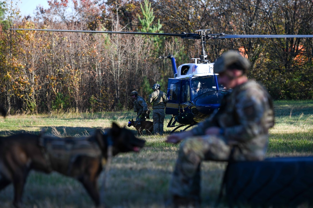 Military Working Dog teams line up in front of a helicopter