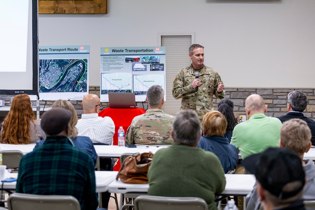A man presents a slideshow to a community audience inside a building.