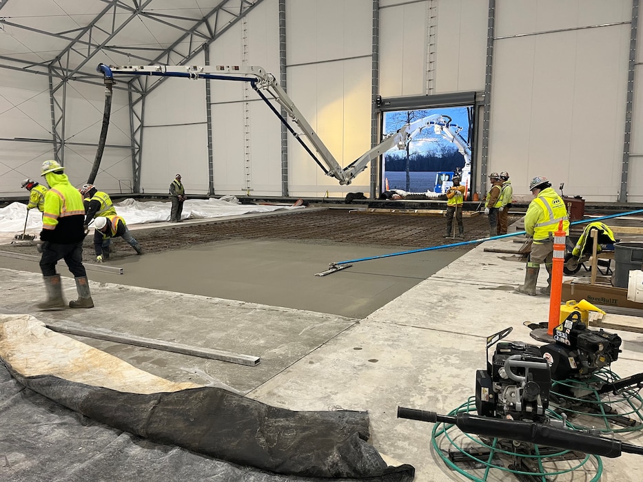 Construction workers work inside a tented building.