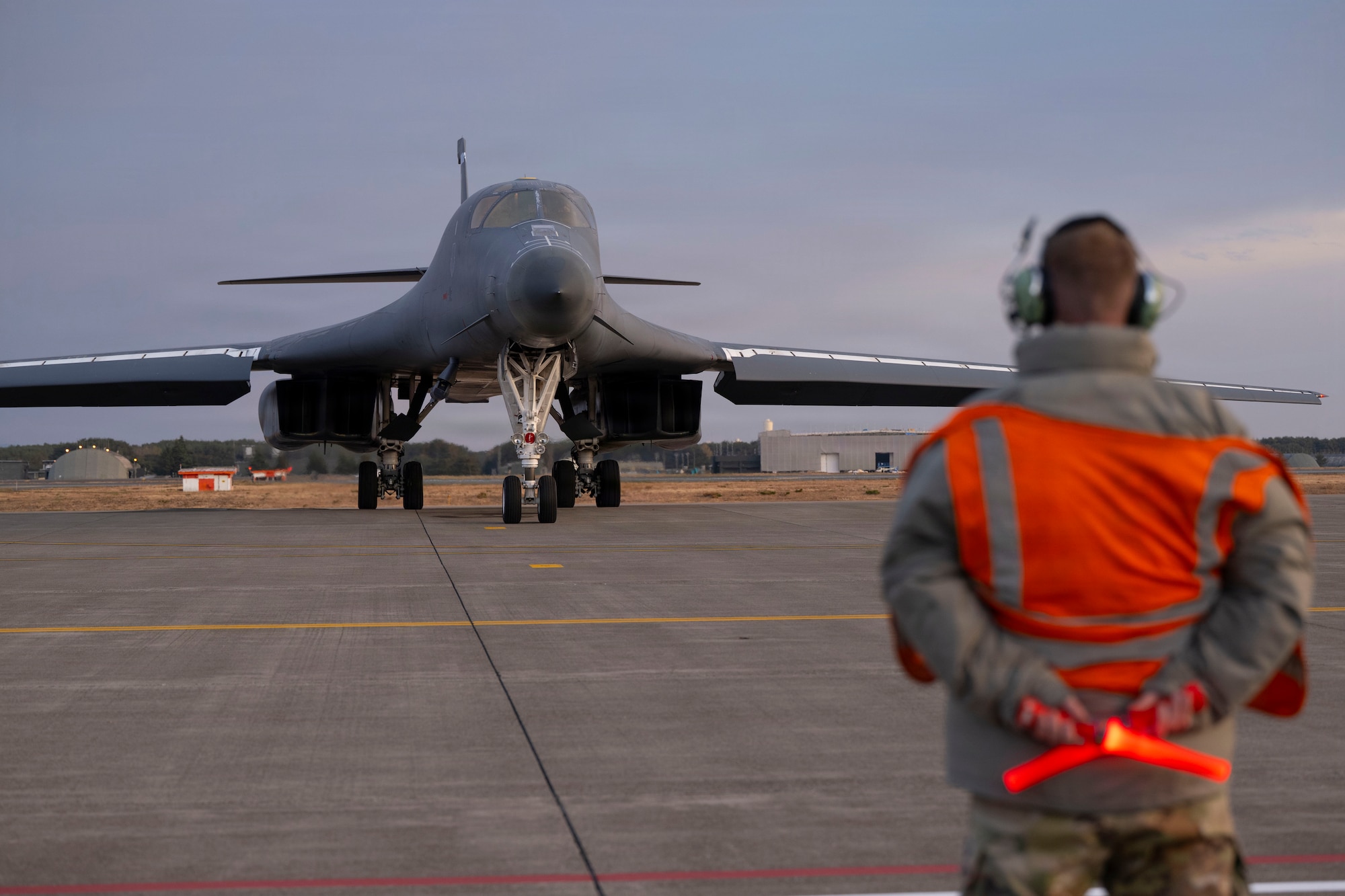 U.S. Air Force Capt. Gunnar Hatzenbiler, 9th Expeditionary Bomb Squadron maintenance officer in charge, prepares to marshal a B-1B Lancer for its return to Dyess Air Force Base, Texas, at Misawa Air Base, Japan, Nov. 17, 2025, concluding a bomber task force deployment. BTFs enhance crew readiness and demonstrate our ability to employ capabilities globally. (U.S. Air Force photo by Senior Airman Emma Anderson)
