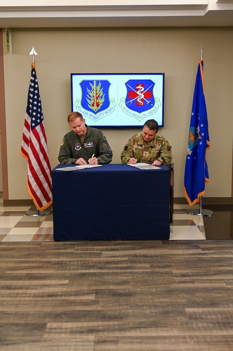 two sitting people sign a document