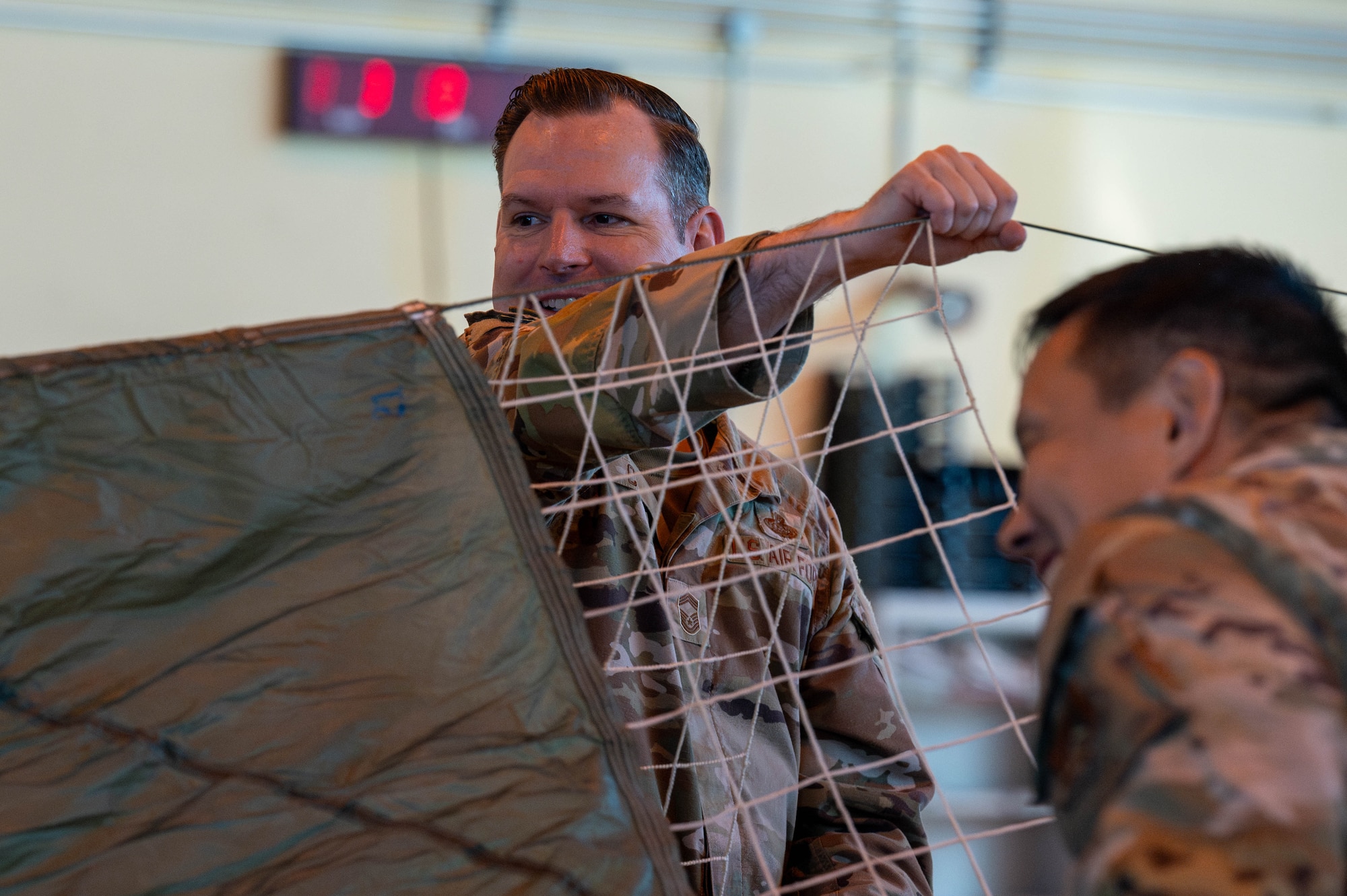 U.S. Air Force Chief Master Sgt. Paul Coleman, 374th Mission Support Group senior enlisted leader, participates in a parachute rigging demonstration.