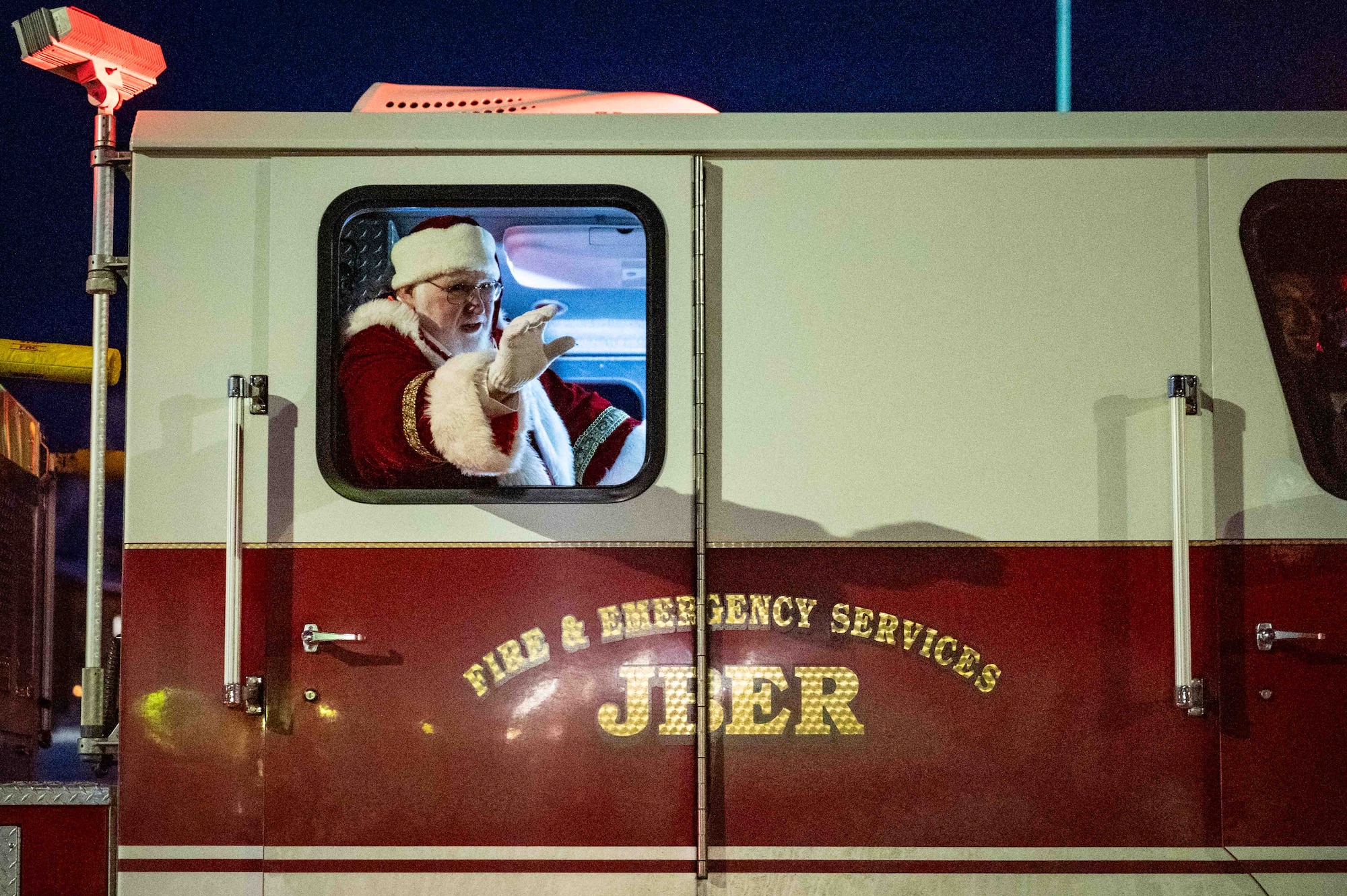 Santa Claus waves from a fire truck assigned to the 673d Civil Engineer Squadron during the annual tree lighting ceremony at Joint Base Elmendorf-Richardson, Alaska, Dec. 2, 2025. The 773d Force Support Squadron hosts the ceremony annually to promote community readiness and cohesion during the festive season. (U.S. Air Force photo by Senior Airman Hunter Hites)