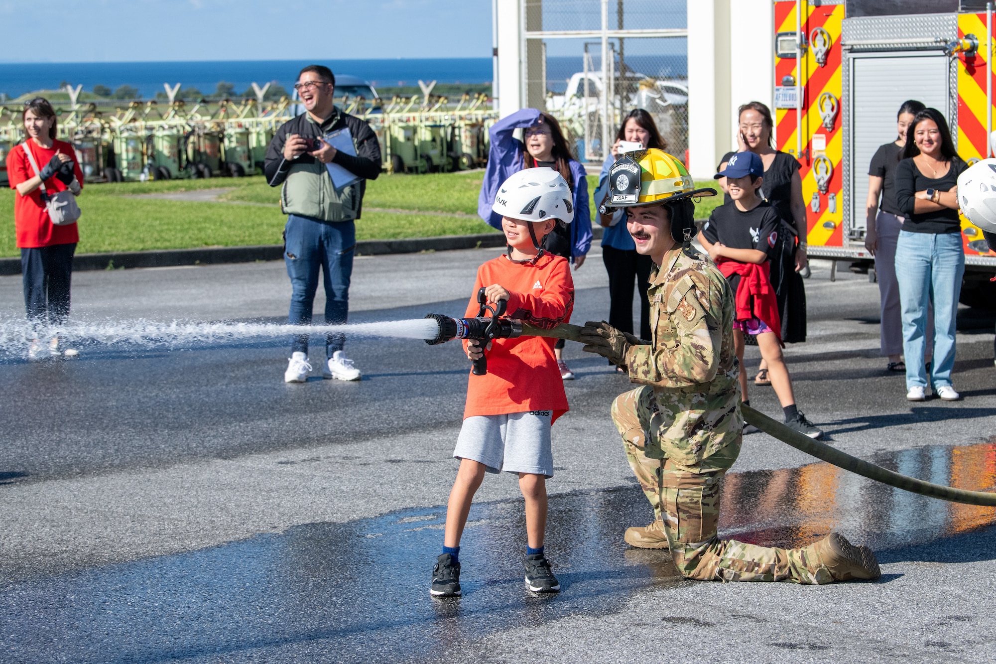 2 people stand hold fire hose