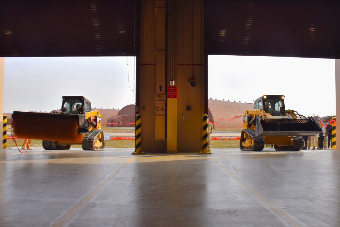 Col. Ryan Ley, Commander, and Chief Master Sgt. Carl T. Vogel, Command Chief, 51st Fighter Wing, drive compact track loaders (CTLs) to clear the ribbon for a new Airfield Damage Repair warehouse, Osan Air Base, on Dec. 3, 2025.
