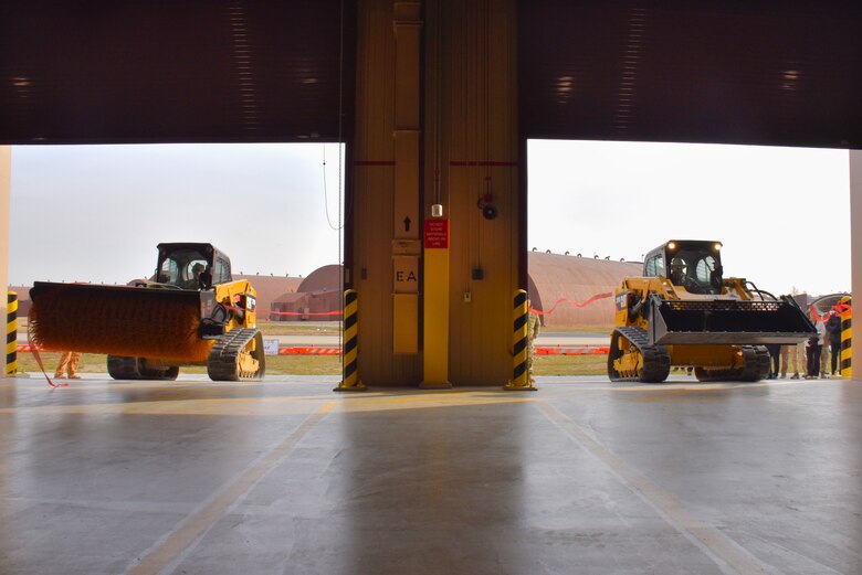 Col. Ryan Ley, Commander, and Chief Master Sgt. Carl T. Vogel, Command Chief, 51st Fighter Wing, drive compact track loaders (CTLs) to clear the ribbon for a new Airfield Damage Repair warehouse, Osan Air Base, on Dec. 3, 2025.