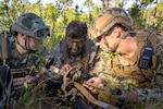 U.S. Marine Corps 1st Lt. Hunter Shrieves, center, an infantry officer with 3rd Battalion, 2nd Marine Regiment, 2nd Marine Division, center, instructs Naval Academy Midshipmen 3rd class Carter Breen, left, and Midshipmen 2nd Class Daniel Reedy, on Marine Corps operating procedures during a Marine Corps Combat Readiness Evaluation on Marine Corps Base Camp Lejeune, North Carolina, Oct. 20, 2025.