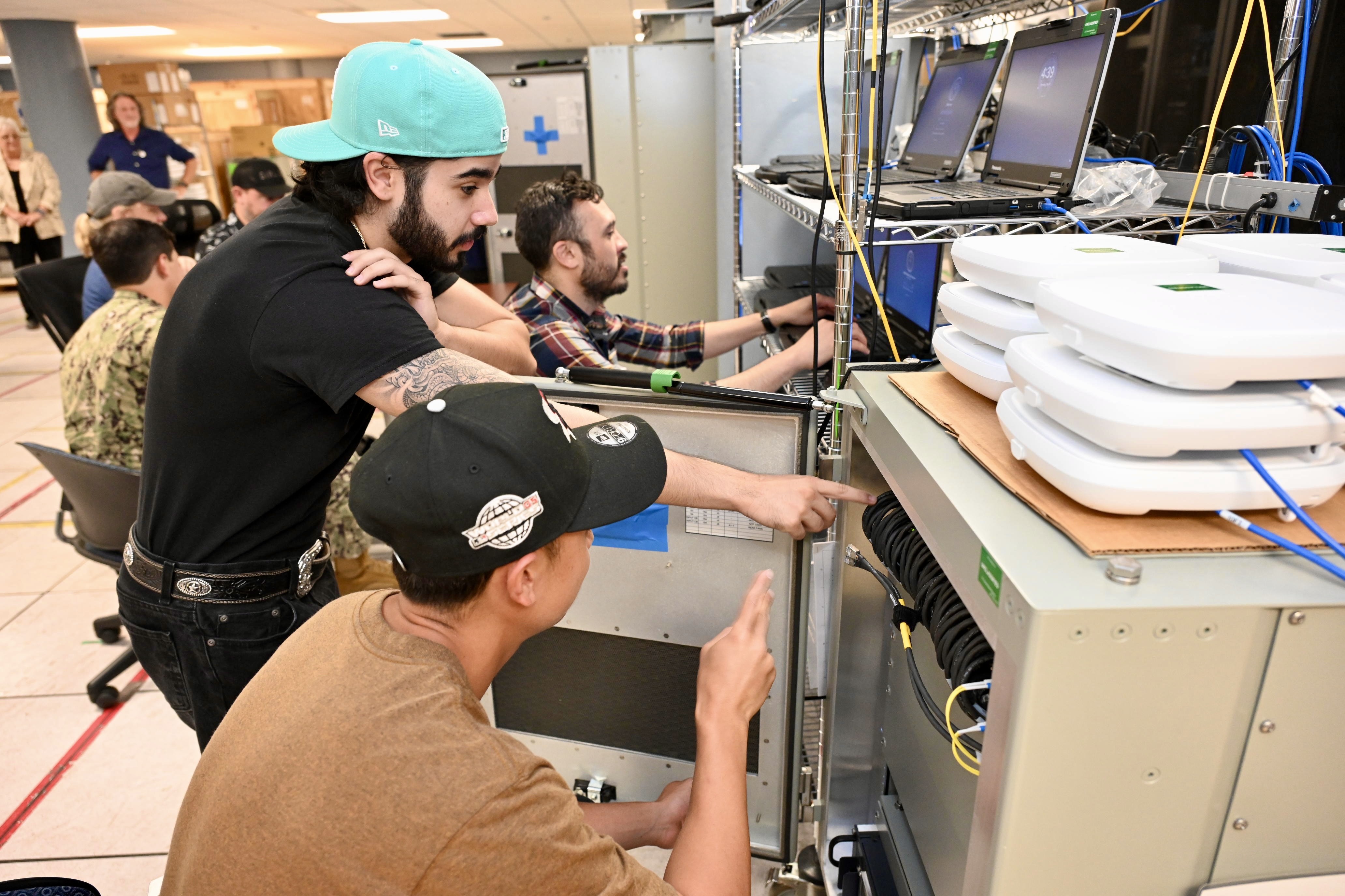 Navy personnel collaborating on network configuration in a lab setting