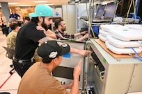 Navy personnel collaborating on network configuration in a lab setting