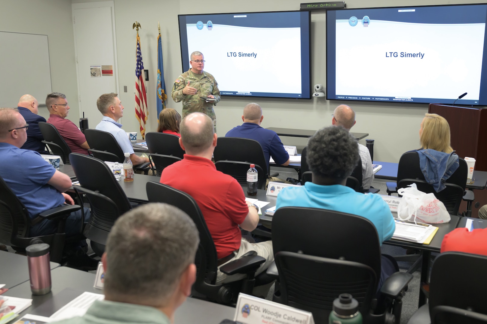 Defense Logistics Agency Director Army Lt. Gen. Mark Simerly stands at the front of a room full of people.
