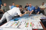 A group of people look at charts and graphs spread out on a table.