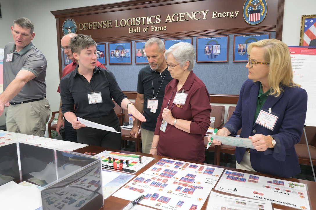 People standing in a group look at documents.