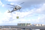 An MH-60S Seahawk helicopter, attached to the "Dragonslayers" of Helicopter Sea Combat Squadron (HSC) 11, transports ordnance from the flight deck of the Nimitz-class aircraft carrier USS Harry S. Truman (CVN 75) to the Lewis and Clark-class supply ship USNS Robert E. Peary (T-AKE 5) during an ammunition offload. Truman is currently underway in the Atlantic Ocean.
