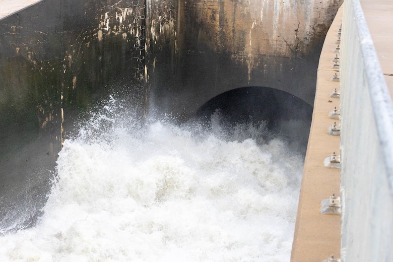 Water flows rapidly out of a brown tunnel.