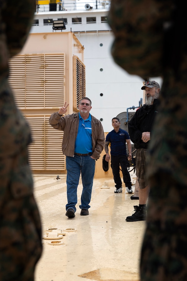 Robert Hazlett, contracting officer's technical representative for Blount Island Command, explains shipboard operations aboard the USNS Sgt. William R. Button during a visit by a Marine Expeditionary Force liaison team Dec. 2, 2025, at Marine Corps Support Facility Blount Island, Florida. Hazlett, a Marine Corps veteran who served six years in motor transportation and nearly 20 years afloat as a KBR contractor—including six years as a squadron supervisor— became a sworn civilian at Blount Island in 2024. (Official Marine Corps Photo by Dustin Senger)