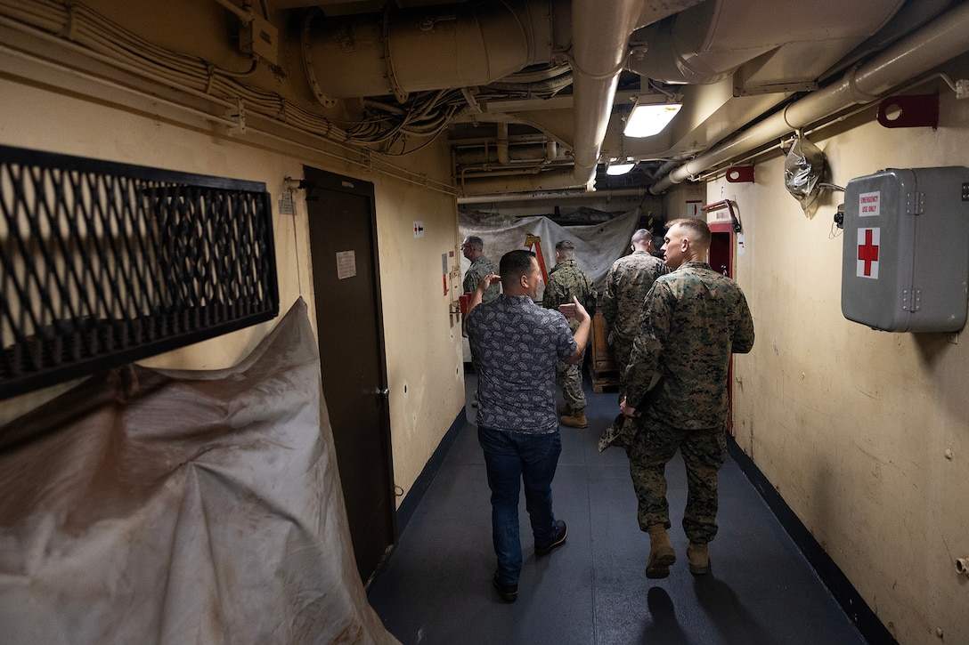 A liaison team from I Marine Expeditionary Force walks down a corridor into the holds of the USNS Sgt. William R. Button during a visit Dec. 2, 2025, at Marine Corps Support Facility Blount Island, Florida. Contractor mariners and Blount Island Command subject-matter experts guided the team through key operational areas to strengthen understanding of prepositioning ship capabilities. (Official Marine Corps Photo by Dustin Senger)