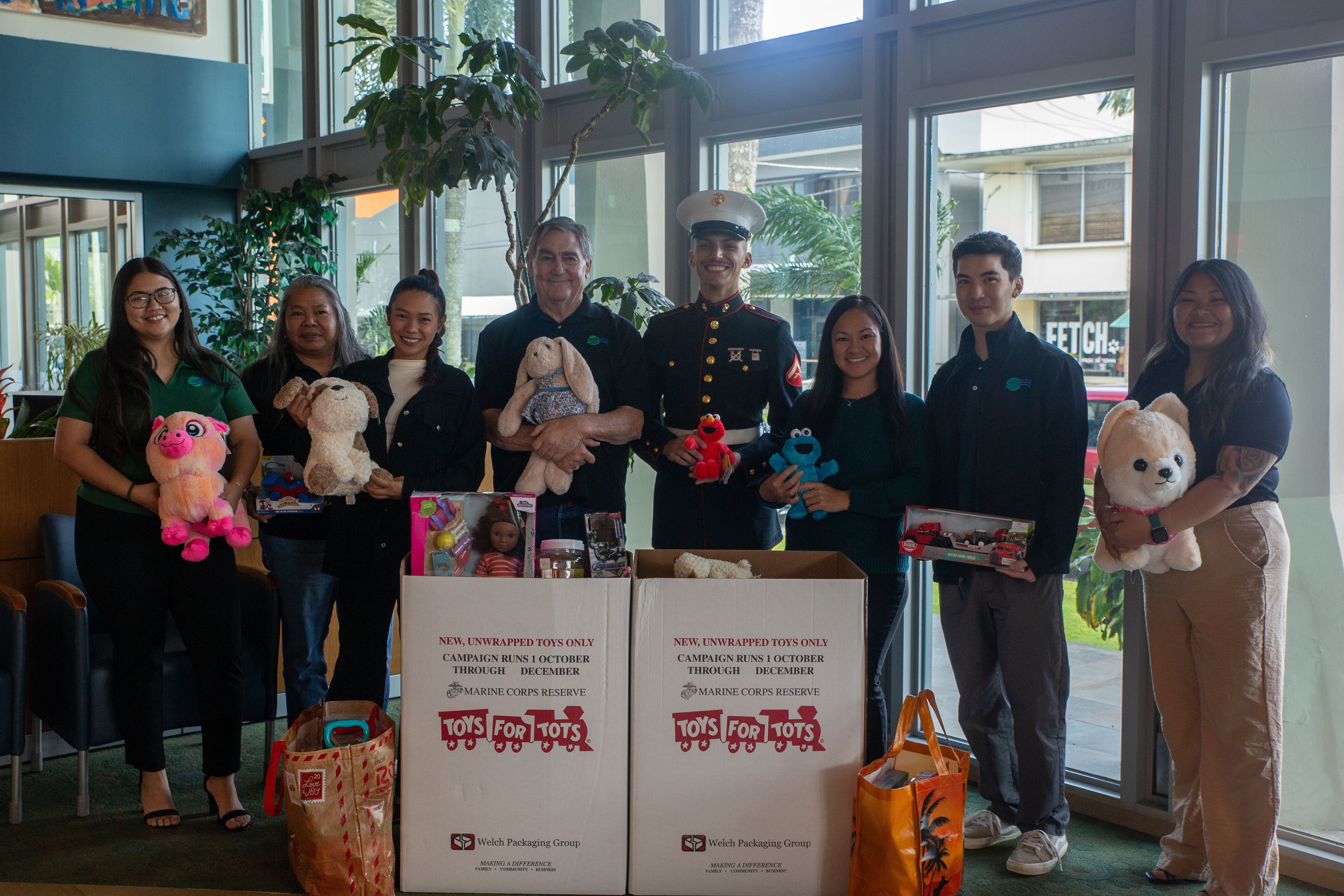 U.S. Marine Corps Lance Cpl. Preston Pacheco, military police, Provost Marshal's Office, Marine Corps Base Camp Blaz, poses for a photo with employees from Bank Pacific during the 2025 Toys for Tots collection, Guam, Dec. 2, 2025. The Marines with MCB Camp Blaz in participation and coordination with the Guam Chamber of Commerce collect new unwrapped toys for distribution to children in the local area and neighboring Commonwealth of the Northern Mariana Islands during the holiday season. (U.S. Marine Corps photo by Lance Cpl. Afton Smiley)