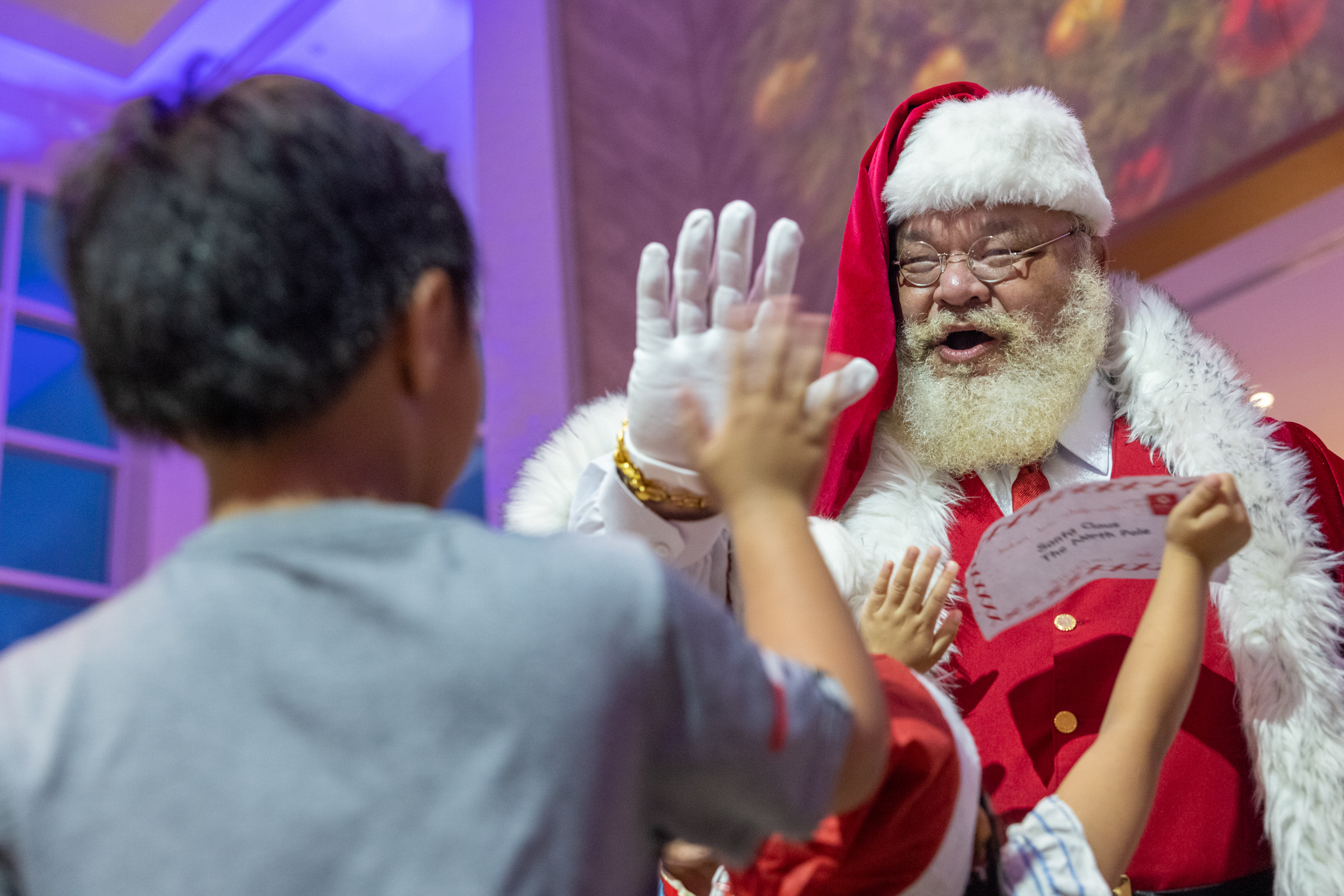 Santa Claus high-fives a child during a Christmas tree lighting ceremony in Tumon, Guam, Dec. 2, 2025. Marines with Marine Corps Base Camp Blaz joined the local community for a Christmas tree lighting ceremony, proudly escorting Santa and supporting the festivities as part of their continued involvement across the island during the holiday season.  (U.S. Marine Corps Photo by Cpl. Ryan Little)