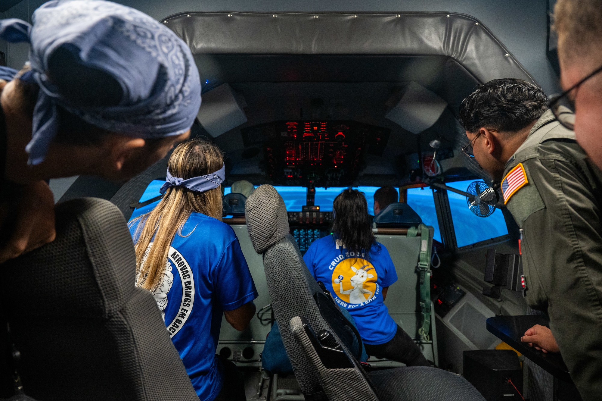 A group of people look out the cockpit of a KC-135 flight simulator.