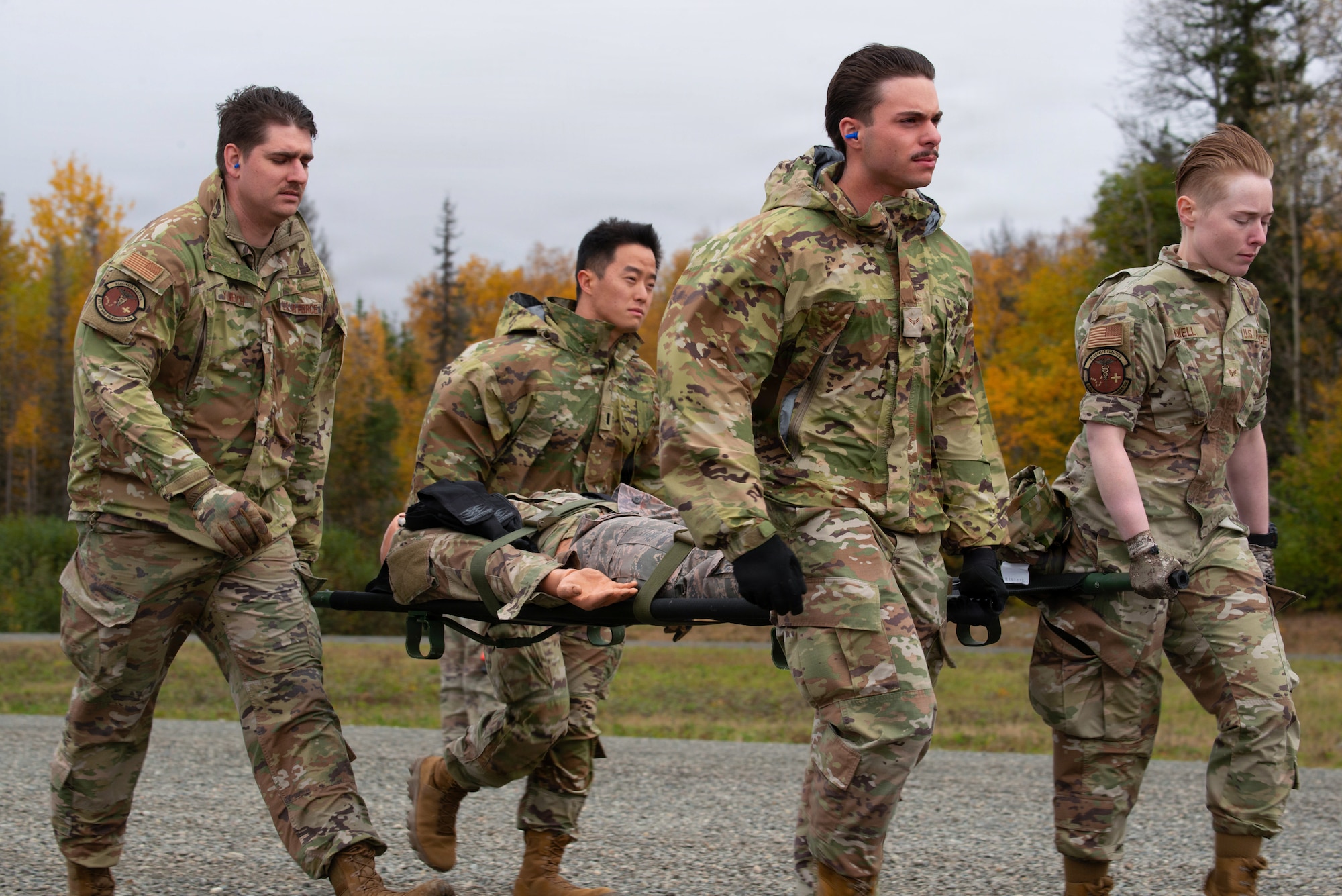 A U.S. Air Force Home Station Medical Response (HSMR) team assigned to the 673d Medical Group carries simulated injured personnel during hands-on emergency medical training on Joint Base Elmendorf-Richardson, Alaska, Sept. 26, 2025. HSMR teams are trained to handle emergencies on base by transporting injured personnel whilst providing medical assistance. The exercise required teams to offload and onload injured personnel from an ambulance bus while providing critical care administration. Readiness among teams is essential to emergency medical situations to allow quicker recovery of injured personnel. (U.S. Air Force photo by Airman Keola Vischi)