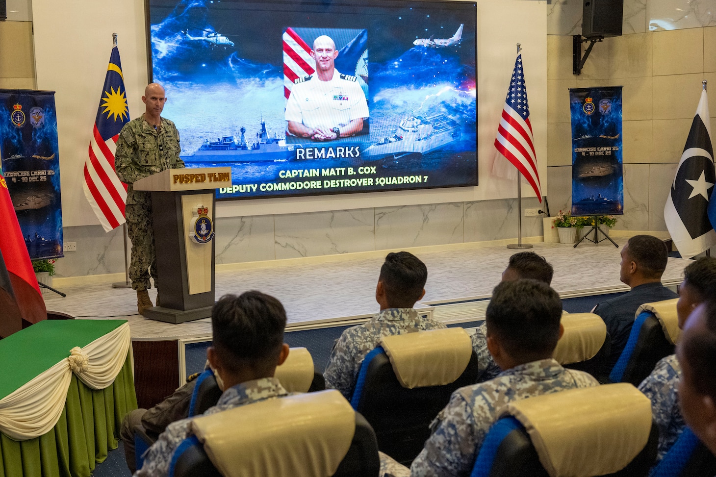 U.S. Navy Capt. Matt Cox, deputy commodore, Destroyer Squadron (DESRON) 7 delivers remarks during the opening ceremony of Cooperation Afloat Readiness and Training (CARAT) Malaysia 2025, at Lumut Naval Base, in Lumut, Malaysia, Dec. 4, 2025. This year marks the 31st iteration of CARAT, a multinational exercise series designed to enhance U.S. and partner navies' abilities to operate together in response to traditional and nontraditional maritime security challenges in the Indo-Pacific region. (U.S. Navy photo by Mass Communication Specialist 2nd Class Anthony Robledo)