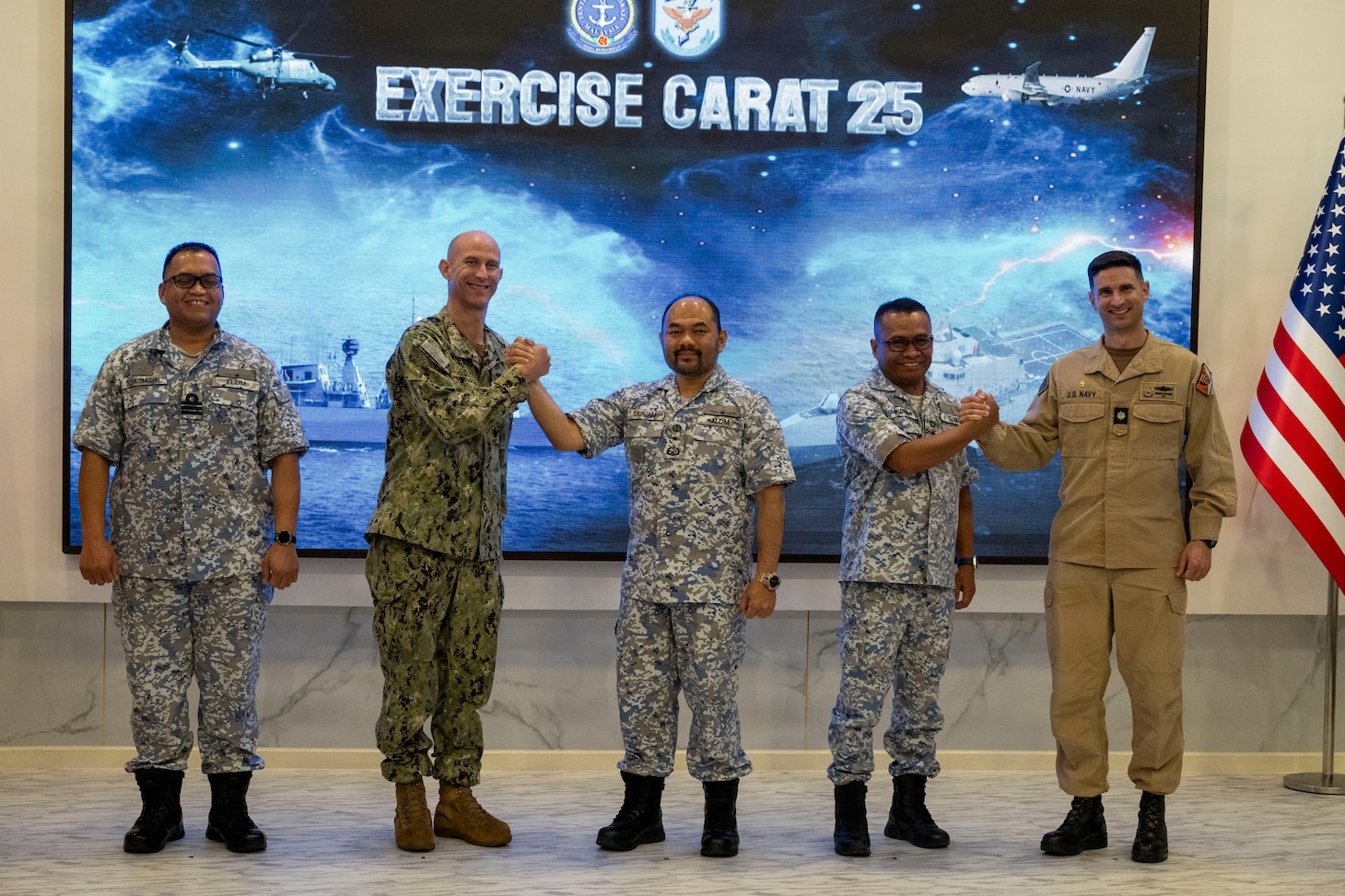 U.S. Navy Capt. Matt Cox, center left, deputy commodore, Destroyer Squadron (DESRON) 7, and U.S. Navy Cmdr. Andrew Recame, right, commanding officer of the Independence-variant littoral combat ship USS Cincinnati (LCS 20), pose for a group photo with Royal Malaysian Navy (RMN) leadership following the commencement of Cooperation Afloat Readiness and Training (CARAT) Malaysia 2025 at Lumut Naval Base, Lumut, Malaysia, Dec. 4, 2025. This year marks the 31st iteration of CARAT, a multinational exercise series designed to enhance U.S. and partner navies' abilities to operate together in response to traditional and non-traditional maritime security challenges in the Indo-Pacific region. (U.S. Navy photo by Mass Communication Specialist 2nd Class Anthony Robledo)
