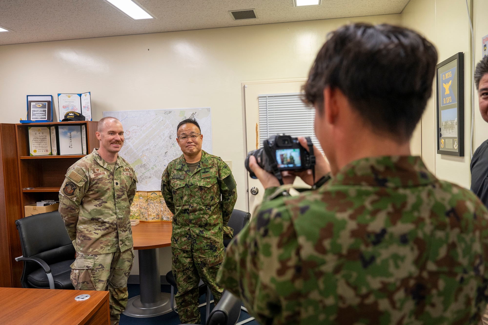 U.S. Air Force Lt. Col. Bradley Robinson, 18th Security Forces commander, left, and Japan Ground Self-Defense Force Col. Masahiro Oda , 51st Infantry Regiment commander, center, pose for a photo during a base tour at Kadena Air Base, Japan, Oct. 25, 2025.