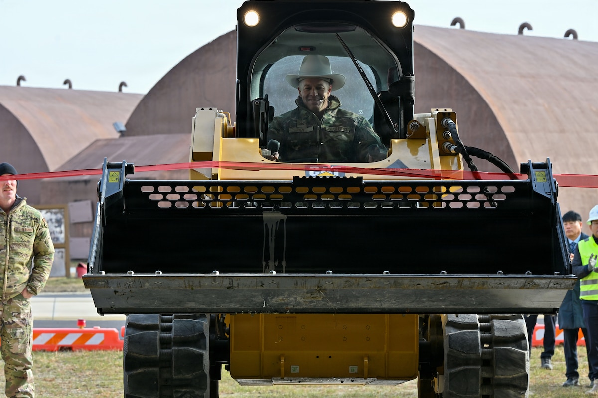 U.S. Air Force Col. Ryan Ley, 51st Fighter Wing commander, drives a compact track loader during a ribbon-cutting ceremony at Osan Air Base, Republic of Korea, December 3, 2025. Upon cutting the ribbon, the warehouse is officially ready for use. (U.S. Air Force photo by Staff Sgt. Dustin Braaten)