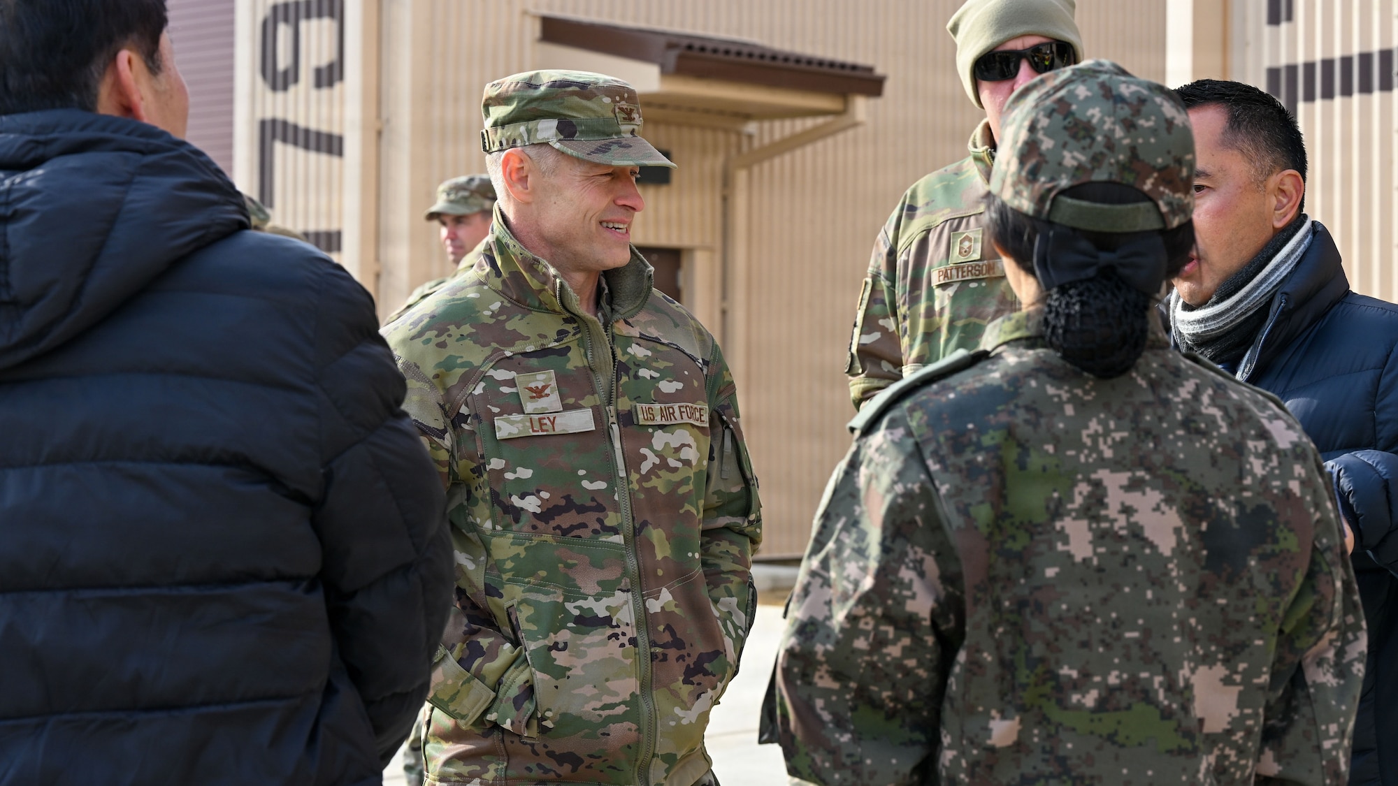 U.S. Air Force Col. Ryan Ley, center, 51st Fighter Wing commander, converses with members assigned to the Republic of Korea Ministry of National Defense-Defense Installations Agency before a ribbon-cutting ceremony at Osan Air Base, ROK, December 3, 2025. MND-DIA funded $30M to construct an airfield damage recovery warehouse to support Team Osan’s mission to “Fight Tonight.” (U.S. Air Force photo by Staff Sgt. Dustin Braaten)
