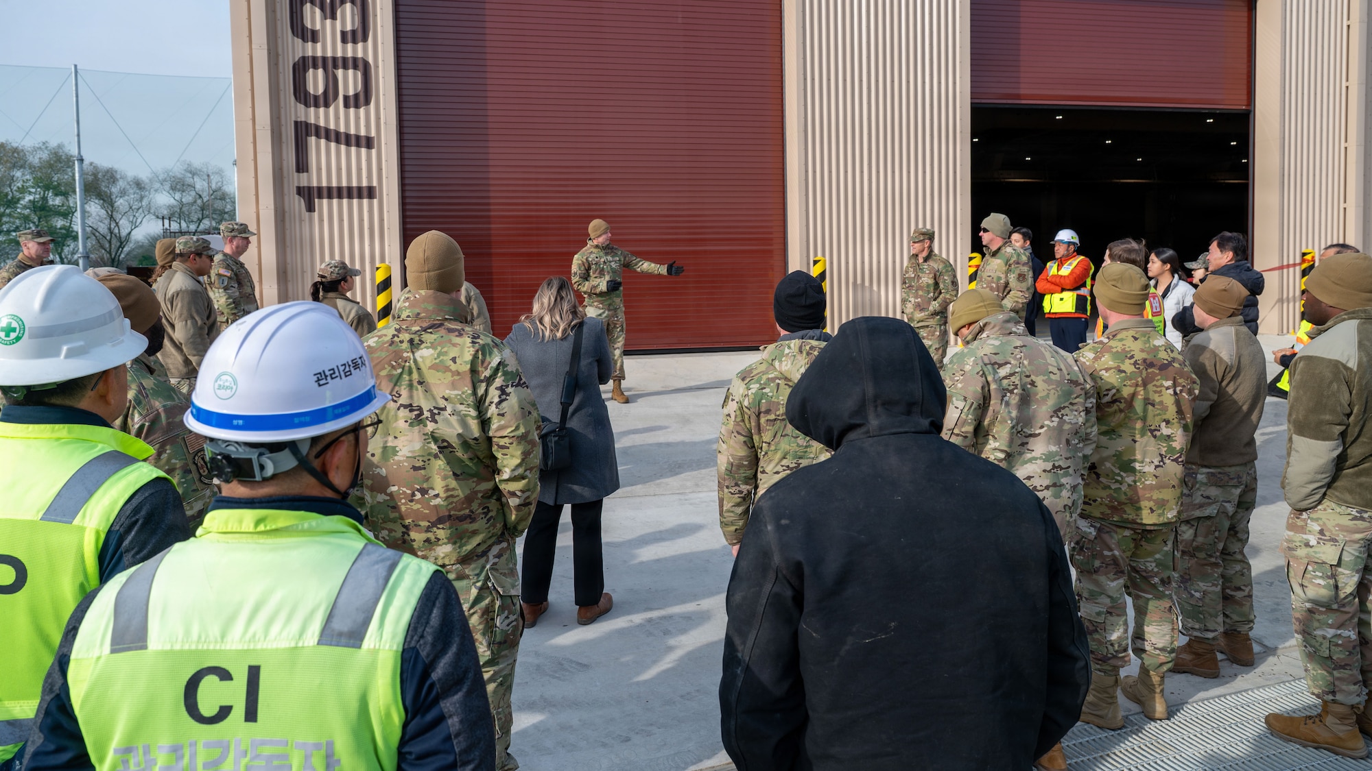 U.S. Air Force Lt. Col Kirk Hull, 51st Civil Engineer Squadron commander, center, introduces Col. Ryan Ley, 51st Fighter Wing commander, to an audience at a ribbon cutting ceremony for a newly-constructed airfield damage repair warehouse at Osan Air Base, Republic of Korea, December 3, 2025. ADR facilities are needed to combat existing and future threats to the base by providing the capability to rapidly deploy repair teams within a minimum response time. (U.S. Air Force photo by Staff Sgt. Dustin Braaten)