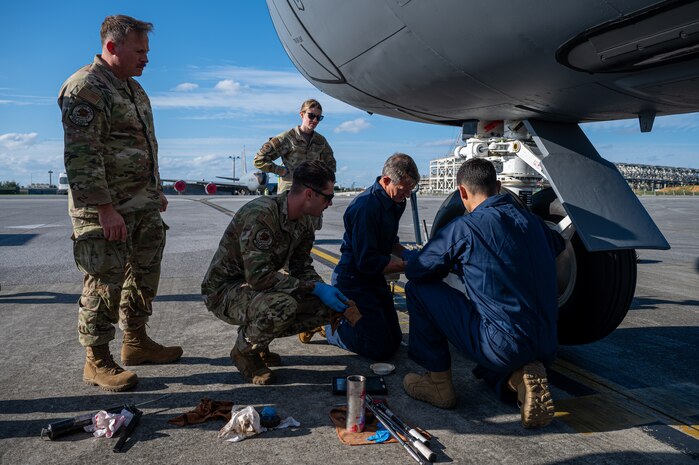 Members of the 18th Wing leadership team secure the tire of the nose landing gear of a KC-135 Stratotanker