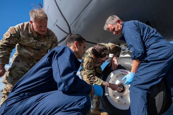 U.S. Air Force Staff Sgt. Alex Farwell, center, 909th Aircraft Maintenance Unit KC-135 Stratotanker crew chief, and the 18th Wing leadership team conduct a water intrusion check on the nose landing gear of a KC-135