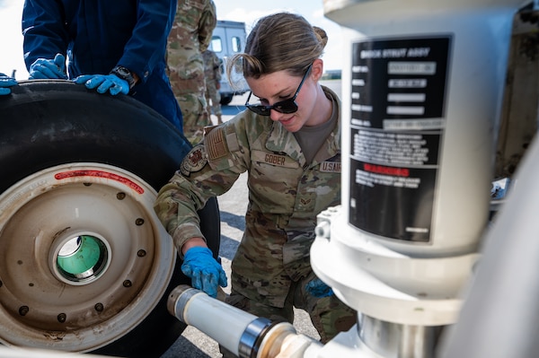 U.S. Air Force Senior Airman Gabrielle Gober, 909th Aircraft Maintenance Unit KC-135 Stratotanker crew chief, greases an axle of the nose landing gear of a KC-135