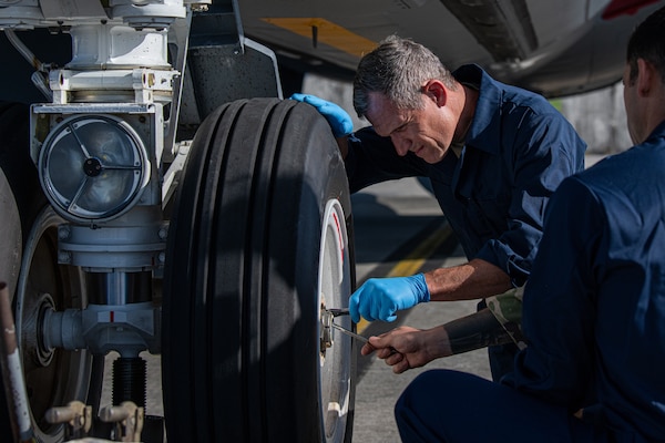 U.S. Air Force Brig. Gen. John Gallemore, 18th Wing commander, conducts a water intrusion check on the nose landing gear of a KC-135 Stratotanker