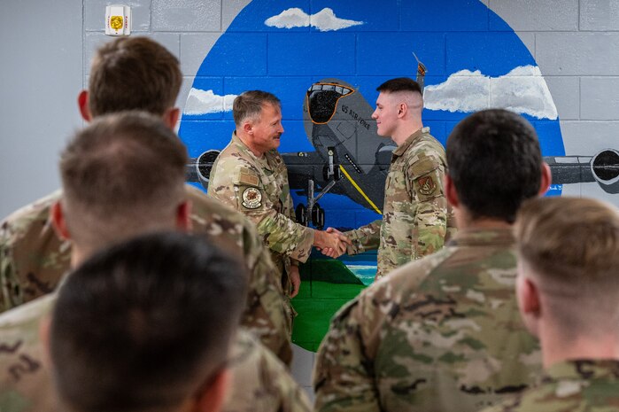 U.S. Air Force Chief Master Sgt. William Cupp, left, 18th Wing command chief presents a coin to Airman 1st Class Nicholas Pueschel, 909th Aircraft Maintenance Unit KC-135 Stratotanker crew chief